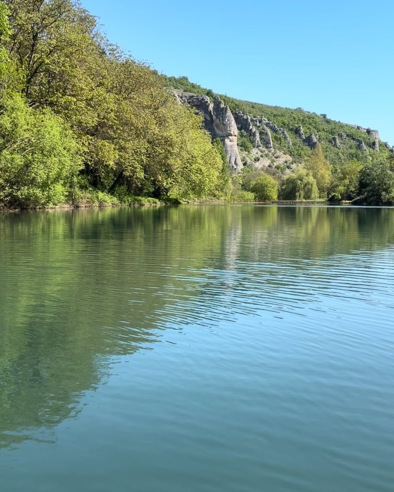 Водата на язовира под варовикови скали и дървета